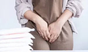 Kobieta zakrywa dłonią okolice intymne, obok stos podpasek. Srom.