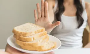Osoba odrzuca talerz z chlebem, pokazując dłoń. To symbol walki z celiakią i unikania glutenu.