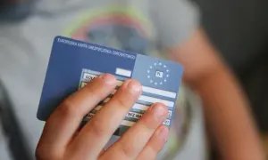Dziecko trzyma Europejską Kartę Ubezpieczenia Zdrowotnego. To ważny dokument, gdy podróżujesz po Europie. Ekuz co to? To Twoje ubezpieczenie zdrowotne.