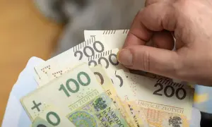 Dłoń trzyma polskie banknoty 100 i 200 zł. Zastanawiasz się, renta wdowia od kiedy można ją otrzymać?