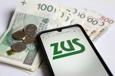 Złotówki i monety na tle ekranu telefonu z logo ZUS. Sprawdzanie opiekun medyczny zarobki.