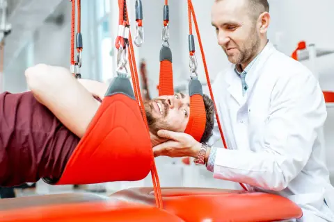 Fizjoterapeuta pomaga pacjentowi z rozszczepem kręgosłupa w terapii wiszącej.