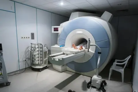 Pacjent leży na stole do rezonansu magnetycznego, gotowy na badanie MR.