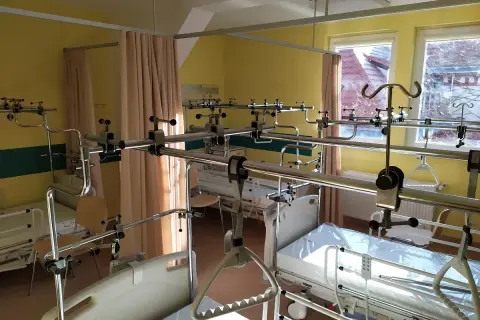 Szpitalna sala z łóżkami i aparaturą ortopedyczną.