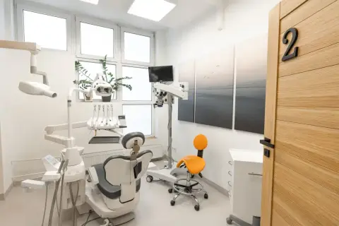 Nowoczesny gabinet stomatologiczny z fotelem dentystycznym, mikroskopem i drzwiami z numerem 2.