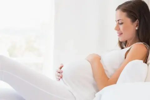 Kobieta w ciąży, która martwi się o konflikt serologiczny, odpoczywa w jasnym pokoju.