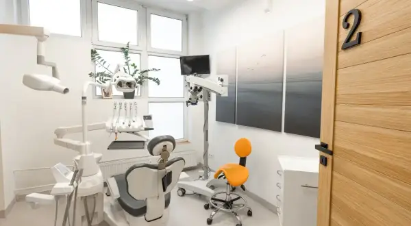 Nowoczesny gabinet stomatologiczny z fotelem dentystycznym, mikroskopem i drzwiami z numerem 2.