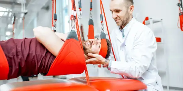 Fizjoterapeuta pomaga pacjentowi z rozszczepem kręgosłupa w terapii wiszącej.